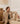 Woman sitting on the floor wearing a beige Masai cardigan and pants in a room with wooden furniture and a map.