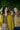 Two women standing outdoors under a tree, one wearing a yellow raincoat and plaid skirt, the other in a patterned top from MD'M fall winter 2025